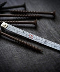 Close-up of Ultra Tiny Titanium Ti Tape Retractable Mini Tape Measure with 3 Feet Range, Imperial and Metric scales next to screws.