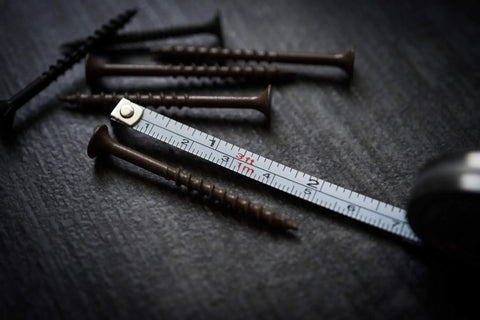 Close-up of Ultra Tiny Titanium Ti Tape Retractable Mini Tape Measure with 3 Feet Range, Imperial and Metric scales next to screws.