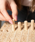 Hand placing hardwood dowels into a board, part of Assorted Wood Dowels Set, Fifty Pcs, Hardwood Dowels In Three Sixteenth Inch, Quarter Inch.