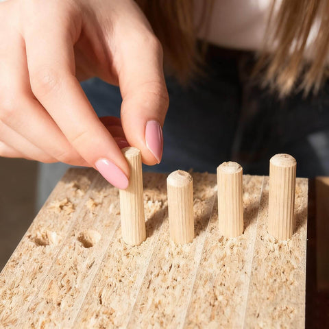 Hand placing hardwood dowels into a board, part of Assorted Wood Dowels Set, Fifty Pcs, Hardwood Dowels In Three Sixteenth Inch, Quarter Inch.