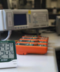 Big Digit Remote Probe Hygro Thermometer With Dual Display showing 70.3°F and 24% RH on a lab table with equipment in background