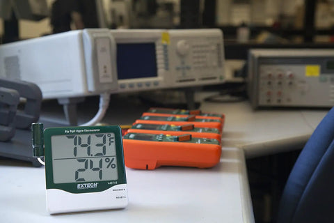 Big Digit Remote Probe Hygro Thermometer With Dual Display showing 70.3°F and 24% RH on a lab table with equipment in background