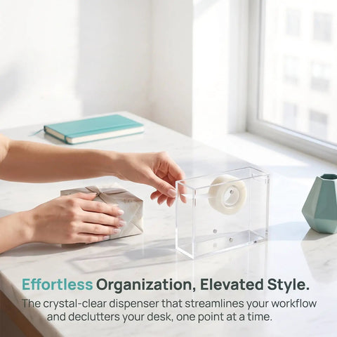 Dual Sided Clear Acrylic Label Roll Dispenser Featuring A Smooth Pull Through Tray on a desk with masking tape.