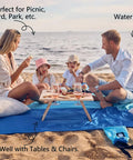 Family enjoying picnic on oversized sandproof beach blanket 10x9 for 2 to 8 adults, showing water resistance and spacious design.