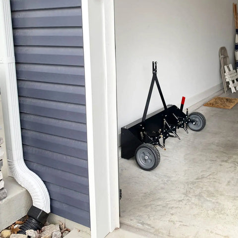 Tow Behind Plug Aerator With Folding Easy Store Tow Bar, 42 Inch Working Width, parked in a garage corner