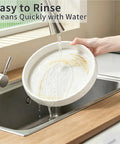 Person rinsing an 11 8 inch Lazy Susan turntable under water in a kitchen sink, showcasing easy cleaning.