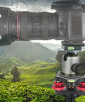 Camera on tripod head with a lush valley background