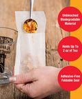 Person filling Disposable Loose Leaf Tea Filters For Easy Brewing, Unbleached Paper Sachets, Single Cup Infuser Bags with loose tea.