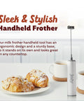 USB Rechargeable Electric Milk Frother Handheld Wand With Dual Speed Stainless Steel Whisk shown on a table with pastries and coffee.