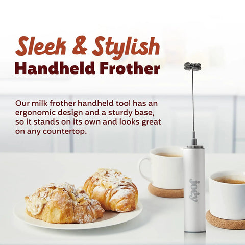 USB Rechargeable Electric Milk Frother Handheld Wand With Dual Speed Stainless Steel Whisk shown on a table with pastries and coffee.