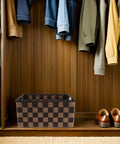 Top Shelf Clothing Storage Bin With Reinforced Metal Frame And Grippy Polyester Weave Handles, placed in a closet, with hanging clothes.