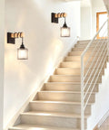 BANGANMA 2-Pack Black Farmhouse Hardwired Wall Sconces Crystal for Bathroom on white wall beside stairs.