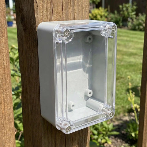 Top-Tier Waterproof Electrical Box Set With Abs Cover For Outdoor Security Modules And Internal Circuits To Keep Stuff Dry And Safe From Rain Sun Or Dust mounted on wood post in garden.