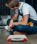 Hella Tough Plastic Parts Organizer Box with red clips used by a technician while fixing equipment on the floor.