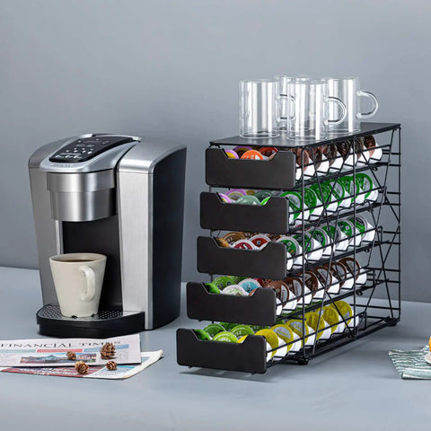 Countertop K Cup Holder Organizer With 105 Pod Capacity, 5 Tiers Of Tilted Slots next to a coffee maker with cups on top