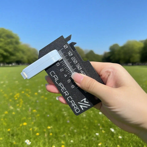 Close-up of hand holding Mini Vernier Caliper Keychain, Portable Millimeter Gauge With Double Scale, black plastic, outdoors