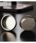 Dope Titanium Espresso Distributor And Ground Leveling Tool For Even Coffee Bed Prep In 58.5mm Portafilter Baskets shown from the side on a dark surface.