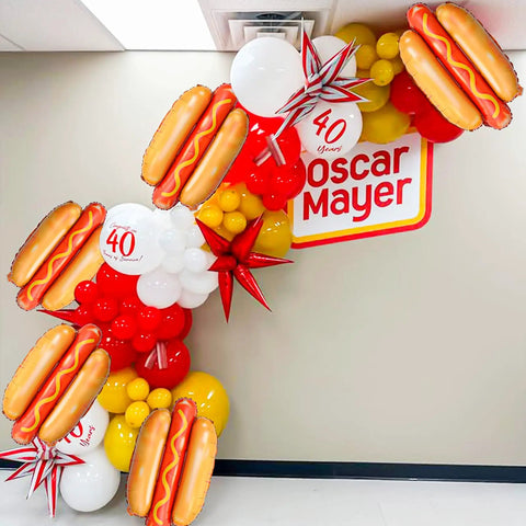 Giant Hot Dog Balloons Set Of 6 28 Inch Food Shape Party Decor displayed with colorful balloons and Oscar Mayer sign.