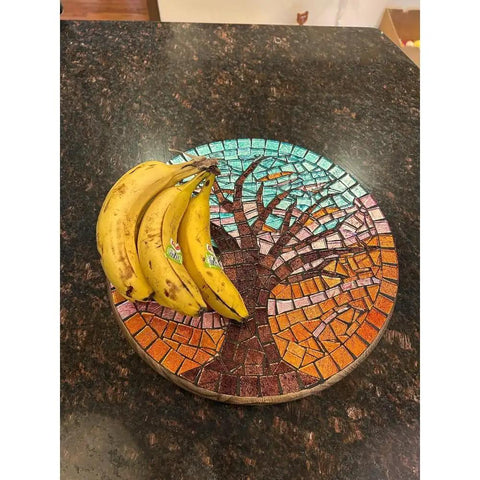 Fifteen Inch Mosaic Tree Of Life Lazy Susan Handcrafted Glass Art Rotating Tray with bananas on brown countertop