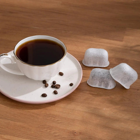12 Pack Replacement Charcoal Water Filter Cartridges For Your Go-To Coffee Brewer Or Machine next to a cup of coffee with beans