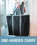 Person carrying Collapsible Laundry Caddy 2 Pack 64L Cream Charcoal Foldable Laundry Basket Organizer with sturdy handles in one hand.