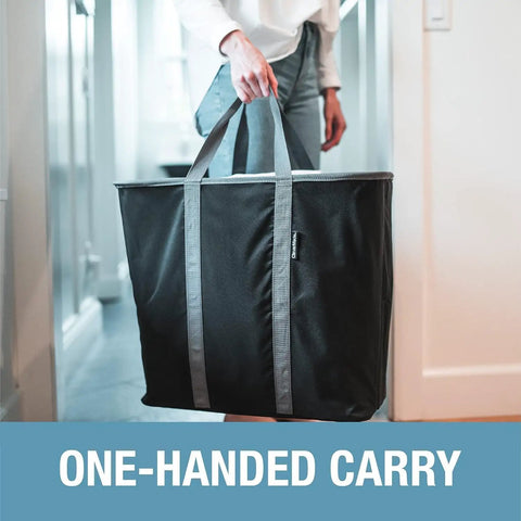 Person carrying Collapsible Laundry Caddy 2 Pack 64L Cream Charcoal Foldable Laundry Basket Organizer with sturdy handles in one hand.