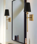 Dope Mid Century Modern Wall Sconce With Black Linen Cone Shade And Warm Brass Finish in bathroom next to mirror