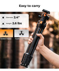 Person holding Travel Ready 63 Inch Aluminum Camera Tripod With Phone Holder, Ultra Light 2.6 Lb, Non Reversible Compact Design