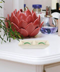 Premium Ceramic Jewelry Dish With Shimmering Gold Trim Dual Grid Holder For Ring And Bling Stash on a vanity with decorative items.