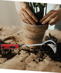 Lightweight Garden Hand Hoe Weeding Tool With Non Slip Handle beside a potted plant and soil in a gardening scene.