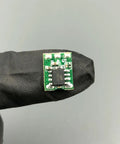 Rock Solid High Torque Coil Actuator With Conversion Board Set, compact green circuit board held in black glove, for DIY RC projects.