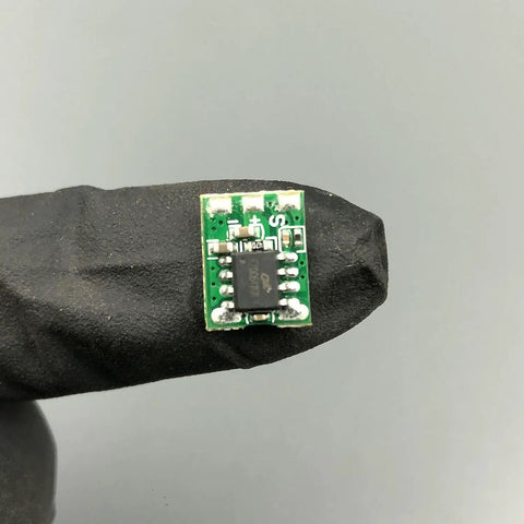 Rock Solid High Torque Coil Actuator With Conversion Board Set, compact green circuit board held in black glove, for DIY RC projects.