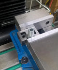 Rock Solid Cast Iron V Block Set For Precision Layout Work And Machinist Bench Setup Featuring Dead Square Ground Edges And Point Zero Zero Zero One Inch Tolerance That Is Seriously Badass Quality positioned on CNC machine with cylindrical part.