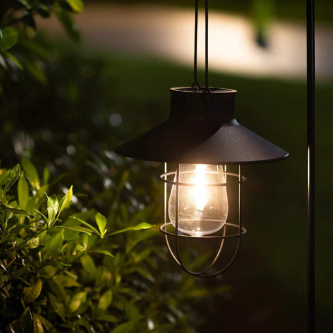 Two Pack Hanging Solar Lantern Lights With Shepherd Hooks Weatherproof Iron Edison Bulb Garden Pathway Lights glowing at night