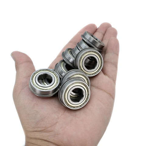 Ten metal precision ball bearings with hex bore held in palm; 1/2 in hex bore, 1-1/8 in OD.