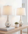 Mercury Silver Glass Table Lamp Set Of 2 With White Linen Shades, 25.5 Inch displayed on a wooden table in a bright room, LED Bulbs Included
