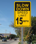 Street view with Slow Down Speed Limit 15 MPH Sign; 12x18 inch reflective aluminum traffic sign displayed on roadside pole.