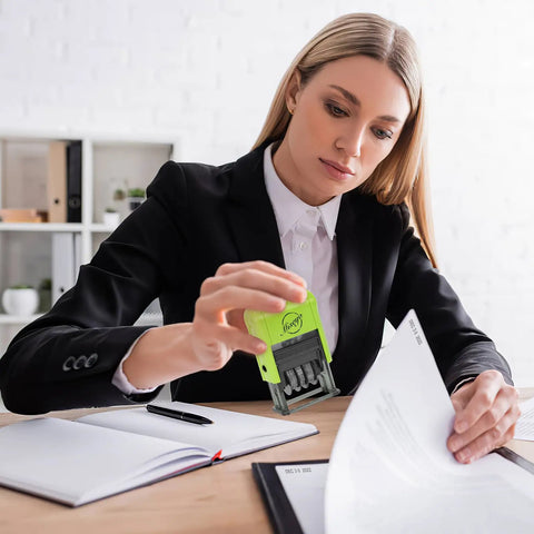 Reliable Self Inking Date Stamp With Rock Solid Green Body And Two Black Refill Pads For Hustling Offices And Home Desks in use on paperwork.