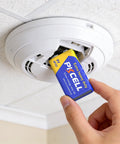 Person installing a Heavy Duty 9V Battery in a smoke detector for secure home safety gear.