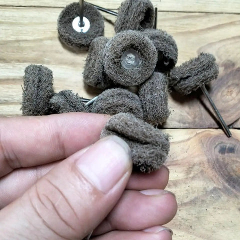 Close-up of a hand holding abrasive nylon fiber buffing pad from 48 Piece Rotary Tool Buffing Wheel Set With Three Thirty Second Inch Mandrels And 2.35 Mm Shanks, Dremel Compatible