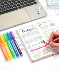 Six Pack Liquid Highlighters With Vibrant Assorted Colors And Clear View Design, Chisel Tip next to opened planner and laptop