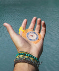 Hand holding Orange Survival Compass With Lanyard The Do It All Hiking Navigator Tool For Outdoor Camping And Backpacking Includes Ruler
