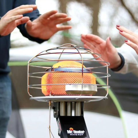 540-Degree 45,000 BTU Tank Top Radiant Propane Heater With Multi Directional Heat, showing safety cage and hands warming outdoors