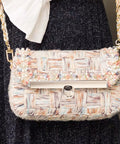 Pastel tweed handbag with gold chain strap and front metal turn-lock clasp.