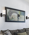 Phoebe 8 Inch Modern Wall Sconce With Frosted Seeded Glass Cylinder Shade For A Dope Industrial Look In Oil Rubbed Bronze Finish Perfect For Bathroom And Hallway Lighting illuminating a living room wall.
