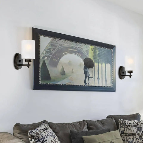 Phoebe 8 Inch Modern Wall Sconce With Frosted Seeded Glass Cylinder Shade For A Dope Industrial Look In Oil Rubbed Bronze Finish Perfect For Bathroom And Hallway Lighting illuminating a living room wall.