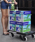 Straight Up Heavy Duty Metal Platform Cart With Four Cushioned Wheels Folding Utility Dolly transporting boxes in a warehouse.