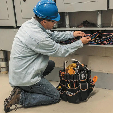 Electrician working with wires beside a Beefy Bucket Tool Bag That Fits A 5 Gallon Bucket With 45 Pockets And Chain Tether Double Layer Polyester