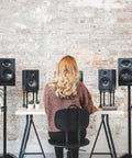 Person seated at a desk with iD14 MKII USB-C Audio Interface with 2 Class-A Mic Preamps and speakers in a studio setup.
