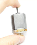 Close-up of a hand holding one motor from the 10 Pack DC Motors 3V To 6V 130 Size Mini Electric Motors 15000 RPM For Arduino DIY Projects And Science Experiments High Quality Mini Motors In A Sturdy Box